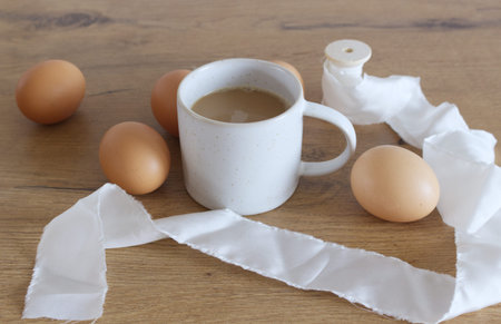 Cozy Easter, spring still life scene. Composition with a mug of coffee and chicken eggs on a wooden table. Vintage feminine-styled photo. Spring concept.の写真素材