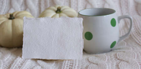 Cozy autumn morning breakfast in bed still life scene. A steaming cup of hot coffee, two white pumpkins and a white card in the foreground. Fall, Thanksgiving concept.Side view. Autumn concept.の写真素材