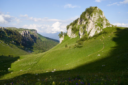 Landscape with green mountain pass surrounded by rocks at sunset.の写真素材