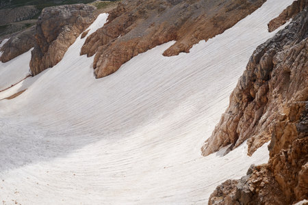 High mountain gorge covered with melting glacier in summer.の写真素材