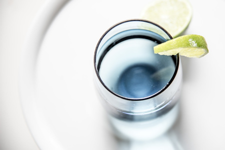 Glass of water with slice of lime, closeup, top view. Water in blue glass with lime macro, white background, horizontal.の写真素材