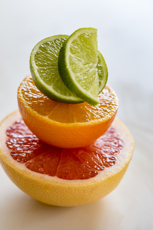 Colorful pile of half citrus fruit, top view, macro. Grapefruit, orange and lime fruit half, macro, vertical.の写真素材