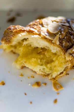 Almond half croissant in white paper box, macro Pastry half, almond, crumbs, closeup, white background.の写真素材
