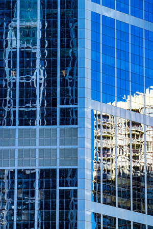 Modern architecture concept, skyscrapers reflections in high rise building. Abstract highrise office building reflecting in blue glass facade.の写真素材