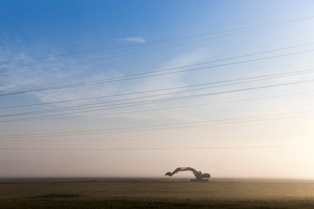 Excavator standing in the field of on-site work performed in the morning of the day in the fog