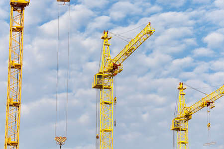 photographed close-up construction cranes during construction of a new multi-storey apartment building, blue sky and clouds,の写真素材