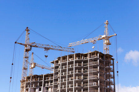 photographed close-up construction cranes during construction of a new multi-storey apartment...