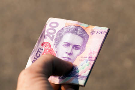 photographed close-up of two hundred Ukrainian hryvnia are in a man's hand, small depth of fieldの写真素材
