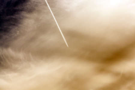 the plane photographed during flight in the sky, visible white lines from the engines, defocusedの写真素材