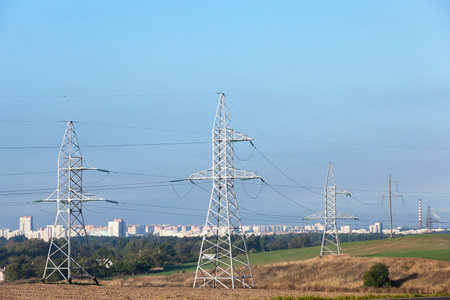 photographed electric poles located in the field during the day against the blue sky, industrial...