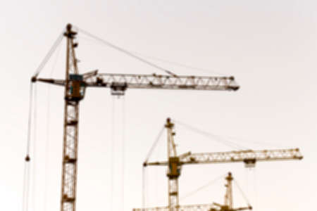 photographed close-up construction cranes during construction of a new multi-storey residential building, multi-colored sky during sunset, defocusの写真素材
