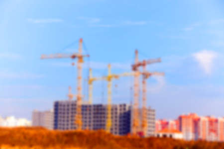 photographed close-up construction cranes during construction of a new multi-storey apartment building, blue sky and clouds, defocusの写真素材