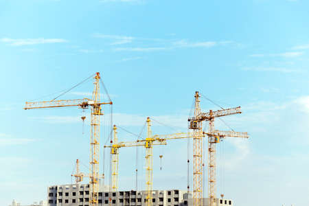 photographed close-up construction cranes during construction of a new multi-storey apartment building, blue sky and clouds,の写真素材