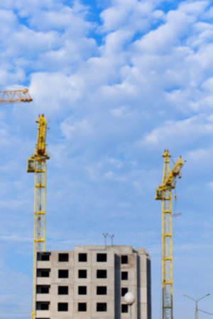 photographed close-up construction cranes during construction of a new multi-storey residential...