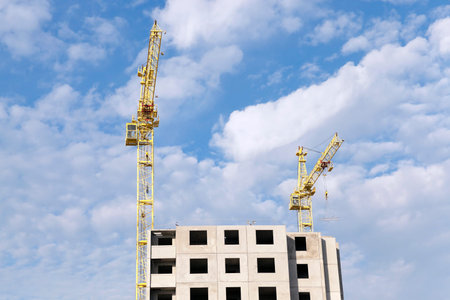 photographed close-up construction cranes during construction of a new multi-storey residential...