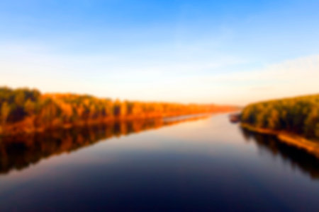the river photographed during the autumn season, the yellowing trees, sun time dawn, defocused