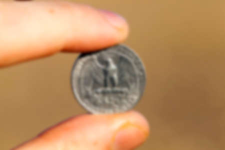 photographed close-up of a quarter of the US dollar in the hands of a man, defocusedの写真素材