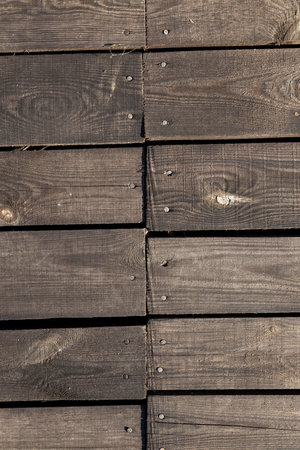 photographed close-up part of the wall made of planks, visible metal nails for attaching...