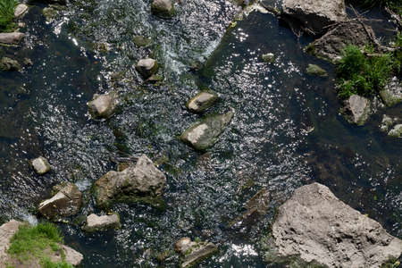 a small river with a rapid current at the bottom of which lie large and small stones. Photo close upの写真素材