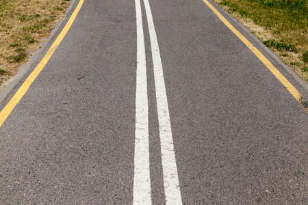 Asphalted road divided into two stripes by white lines. On the edge of the road yellow linesの写真素材