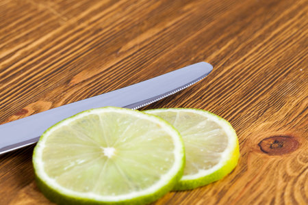 Pieces of lime and a knife on an old wooden boardの写真素材