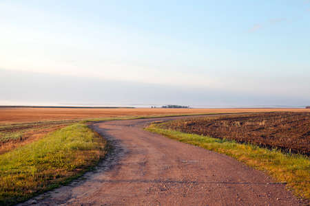 a country road without asphalt with a number of turns. The photo was taken in the morning in the summer season during a small fog in the distance and a bright blue skyの写真素材