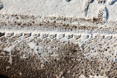 close-up photo of a road in the winter season. On the dirty snow, a protector is visible from the tires of the truck.の写真素材