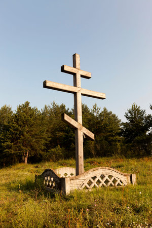 close-up photograph of a wooden religious Christian cross set near a forest. Blue sky in the backgroundの写真素材