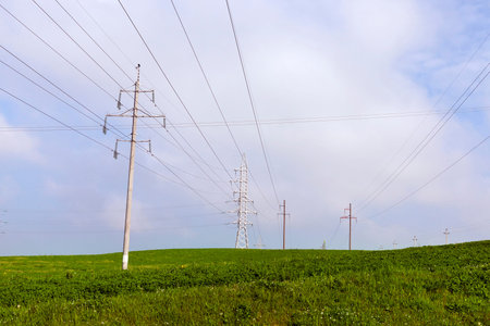 Poles with electric lines built in an agricultural field. Photo in the spring day
