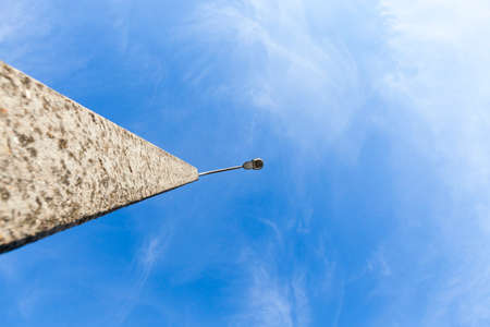 close-up photo of an old concrete pillar on which a night light lamp is fixed. The sky is blueの写真素材