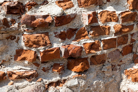 a broken brick wall of orange color. Photographed close-up.
