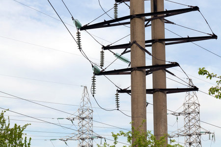 Two thick stone and several metal pillars through which pass the high-voltage lines. Daytime, photo...