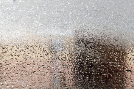 photo of a frost on the car's glass in the winter season. Rubbish, mud and other are visible on the...
