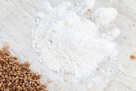 white flour and whole wheat grains lying in a pile on white wheat pita bread. photo close-up on topの写真素材
