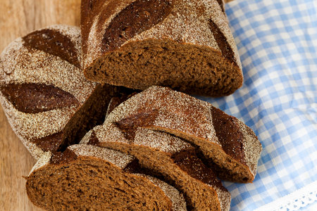 One loaf of rye bread, divided into slices during the preparation of dinner. Photo close-up of food lying on a table and a paper napkinの写真素材