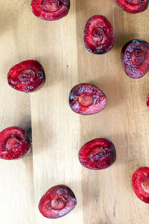 Divided into half a beautiful mature and juicy cherry, lying on an old wooden table. inside the pulp lie solid bones. photo close-up, top view from the sideの写真素材