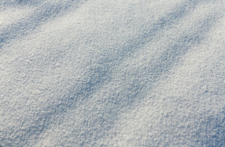 deep snowdrifts of white snow after snowfall. photo close-up. On the surface there are dark bands of...