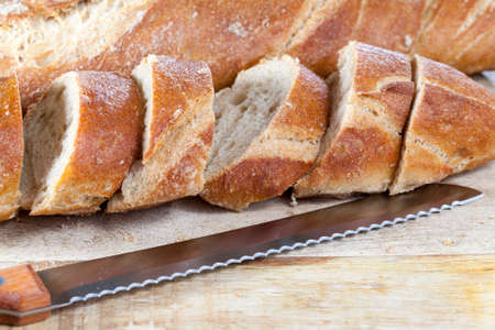 fresh homemade bread, divided into pieces by a knife. photo close-up of food on a cutting boardの写真素材