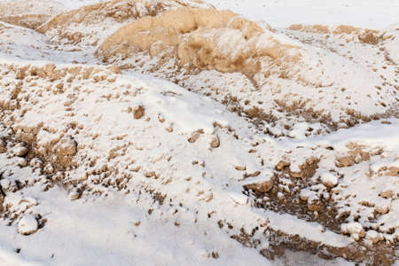 a pile of yellow sand under the snow in the winter season. close-up photoの写真素材