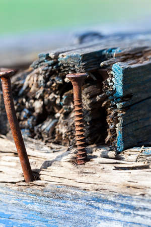 planks and rusty nails from the old broken-up wooden bench placed in the park. In the wood there are traces of blue paint. Photo close-up, small depth of field.の写真素材