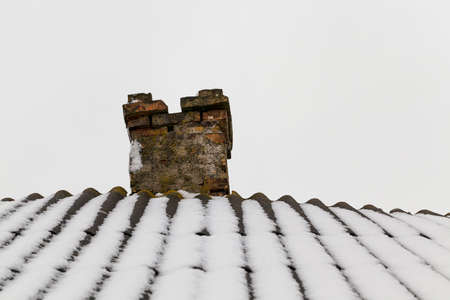photograph of the roof of a house made of slate covered with snow falling during a snowfallの写真素材
