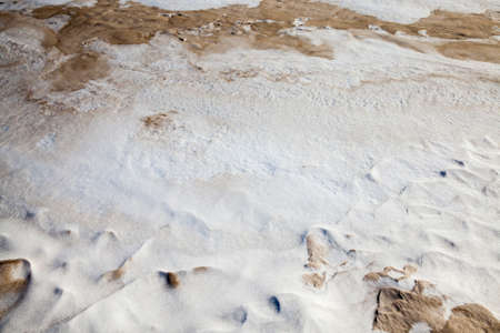 very heavily dirty snow lying on the roadside. photo close-up. on snow drifts yellow soot, dust, dirt and sand. photo close-up in winterの写真素材