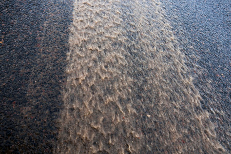 dirty melted snow and slush on the asphalt road in the winter season. photo close-up with a shallow...