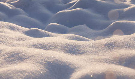 irregularities on the snow surface after a snowfall. To the right of the snowdrifts are visible glare from the sunの写真素材