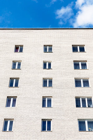 Wall and glazed windows of a building made of light brick, photo of a large part of a block of a...