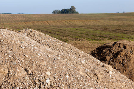 a large pile of sand, gravel and other building materials in the field near the repaired road