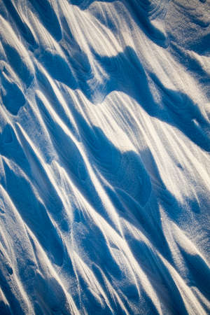 fresh snow formed snow dunes and snowdrifts, lit by the bright sun, shadows formed, close-upの写真素材