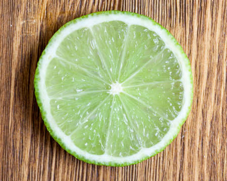 cut across the green lime, laid on a wooden table, closeup of a citrus food, topの写真素材