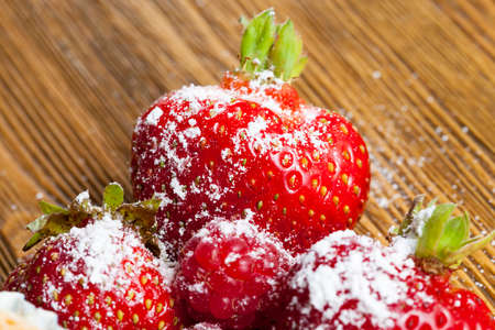 sprinkled with powdered sugar ripe red strawberry berries, lying on a wooden table while cookingの写真素材