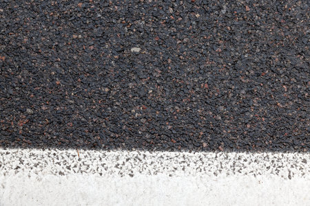wet from the water road after the last rain, separating white strip on the roadway, photo close-up...